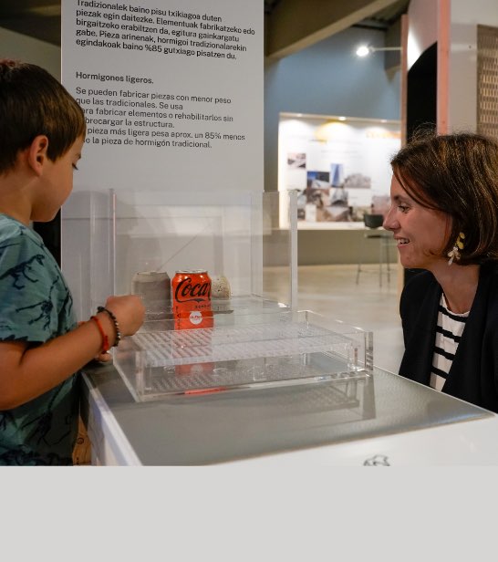 Foto de una madre con su hijo haciendo un experimento con cemento en el Museo Cemento Rezola