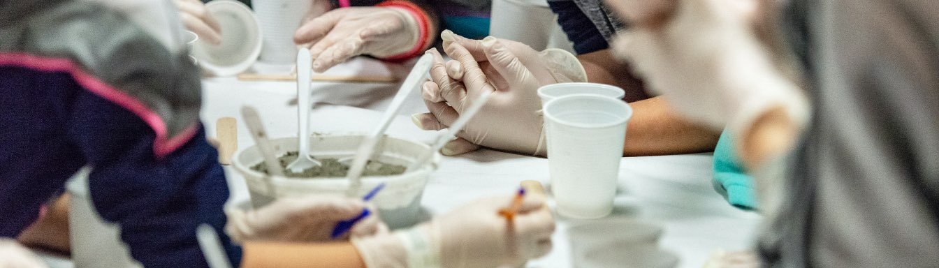 Detalle de varias manos haciendo mini esculturas de cemento en el museo cemento rezola